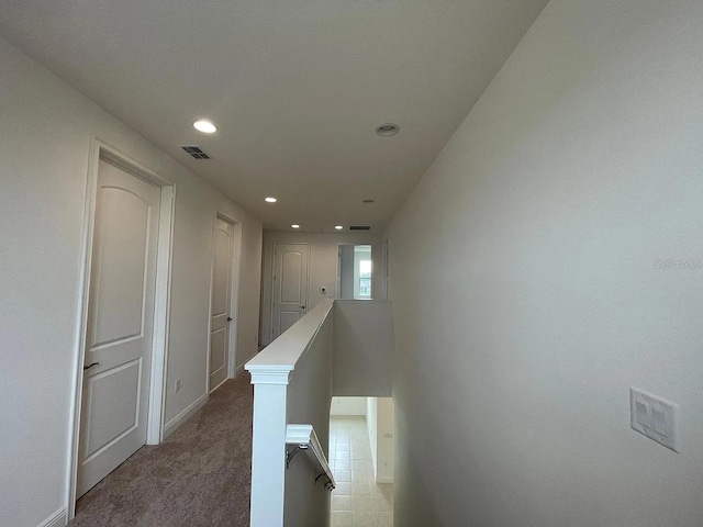 hallway featuring visible vents, baseboards, an upstairs landing, light carpet, and recessed lighting