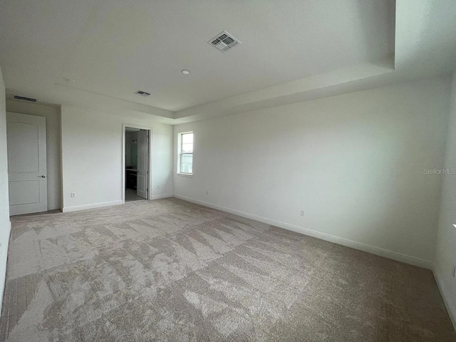 unfurnished room featuring light colored carpet, visible vents, and baseboards