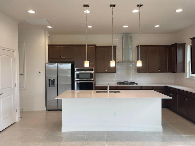 kitchen with a sink, stainless steel appliances, dark brown cabinets, and wall chimney exhaust hood