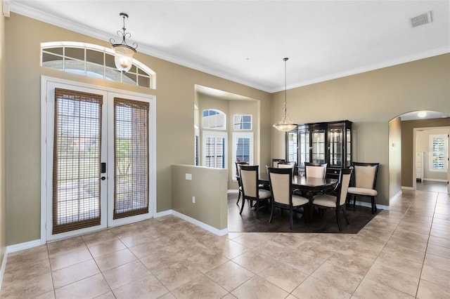 dining area featuring baseboards, visible vents, arched walkways, french doors, and crown molding