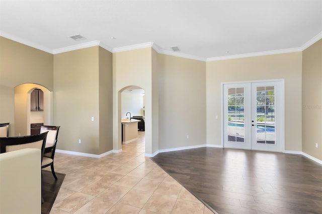 living area with crown molding, visible vents, arched walkways, and french doors