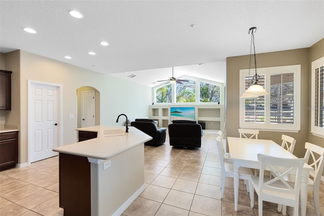 kitchen with light countertops, vaulted ceiling, arched walkways, and a sink