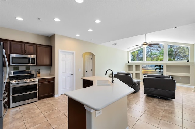 kitchen featuring a sink, arched walkways, appliances with stainless steel finishes, and light countertops