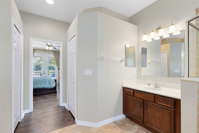 ensuite bathroom with ensuite bath, french doors, baseboards, ceiling fan, and vanity