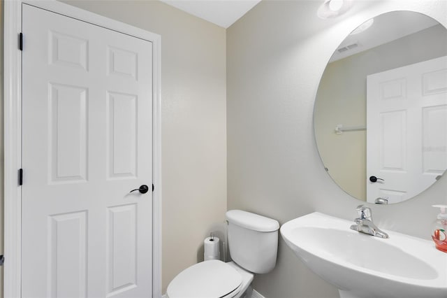 half bathroom featuring a sink, visible vents, and toilet