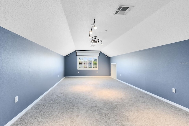 bonus room with visible vents, a textured ceiling, carpet flooring, baseboards, and vaulted ceiling