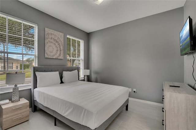 bedroom with light tile patterned floors and baseboards