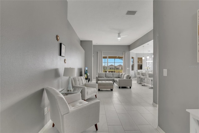 living area featuring baseboards, visible vents, and ceiling fan