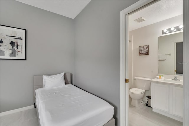 bedroom featuring visible vents, ensuite bathroom, and baseboards