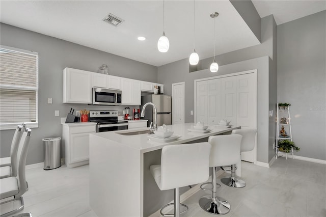 kitchen with visible vents, a breakfast bar, a sink, stainless steel appliances, and white cabinets