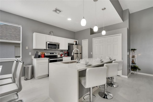 kitchen with a breakfast bar, white cabinets, appliances with stainless steel finishes, and a sink