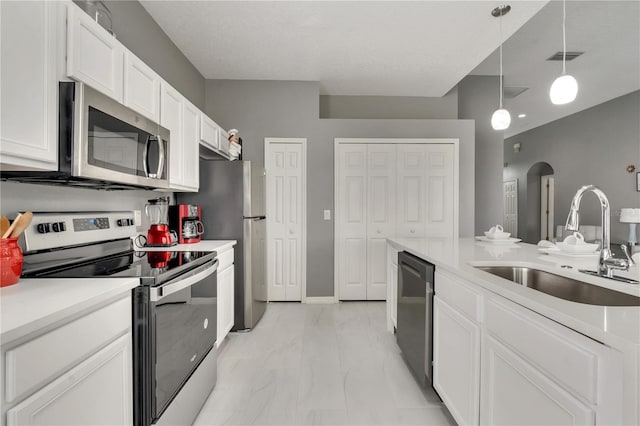 kitchen with a sink, arched walkways, appliances with stainless steel finishes, white cabinets, and hanging light fixtures