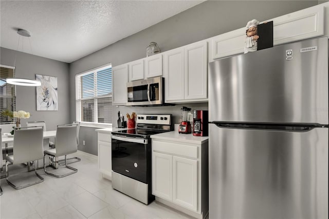 kitchen with white cabinetry, light countertops, decorative light fixtures, and appliances with stainless steel finishes