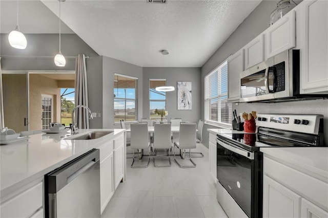 kitchen featuring white cabinetry, stainless steel appliances, light countertops, and a sink