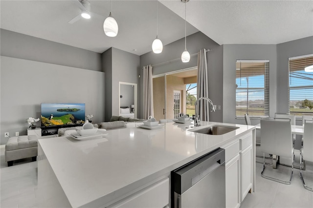 kitchen with stainless steel dishwasher, open floor plan, white cabinetry, and a sink