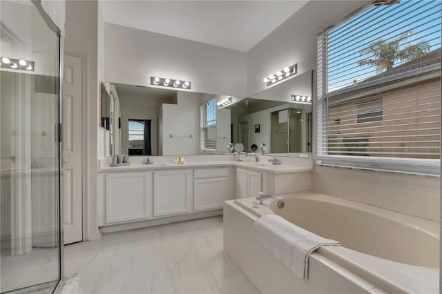 bathroom featuring double vanity, a garden tub, a stall shower, and a sink