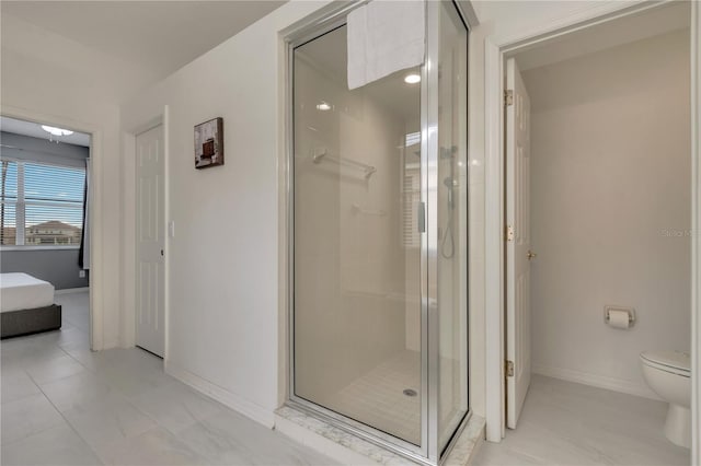 bathroom with baseboards, toilet, and a stall shower