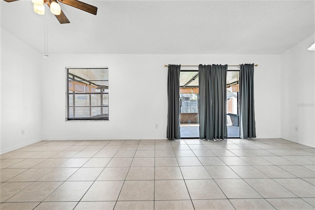 spare room featuring light tile patterned floors, baseboards, ceiling fan, and vaulted ceiling