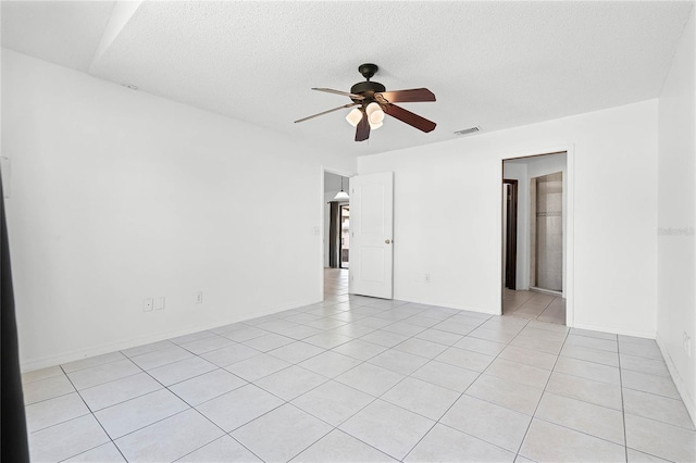 unfurnished room featuring visible vents, arched walkways, light tile patterned flooring, a textured ceiling, and a ceiling fan