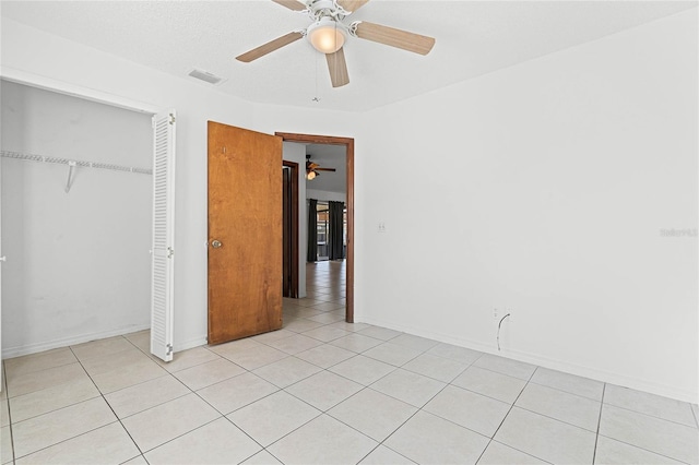 unfurnished bedroom featuring baseboards, visible vents, light tile patterned flooring, ceiling fan, and a closet