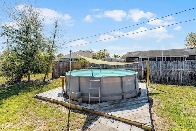 view of swimming pool with a lawn, a fenced in pool, a fenced backyard, and a wooden deck