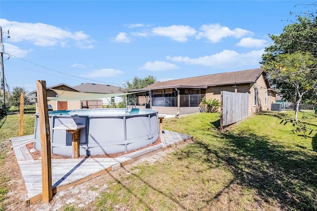 view of yard featuring an outdoor pool, fence, central AC, and a sunroom