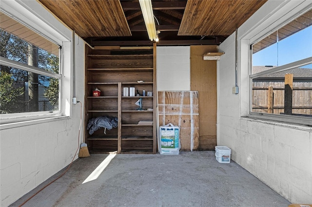 spare room with concrete block wall, wood ceiling, and concrete flooring