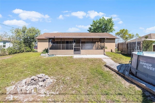 rear view of house featuring a yard, fence, stucco siding, and a sunroom