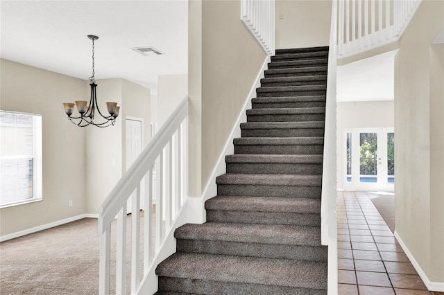 staircase with baseboards, visible vents, tile patterned flooring, carpet flooring, and a chandelier