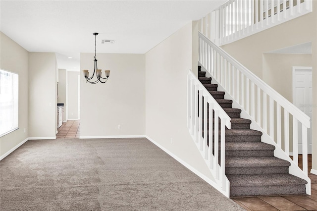 stairway featuring tile patterned flooring, visible vents, baseboards, carpet, and a notable chandelier