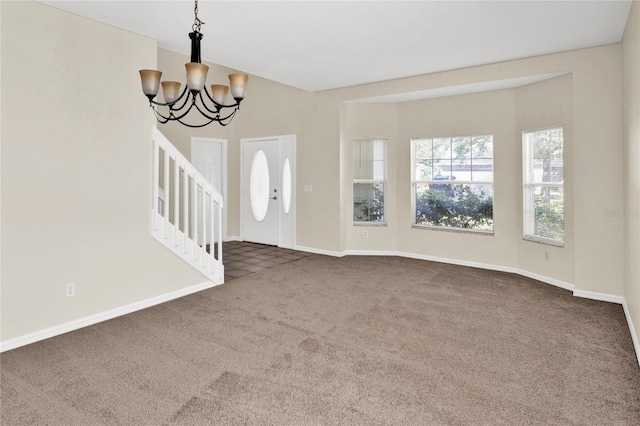 foyer with an inviting chandelier, baseboards, and carpet