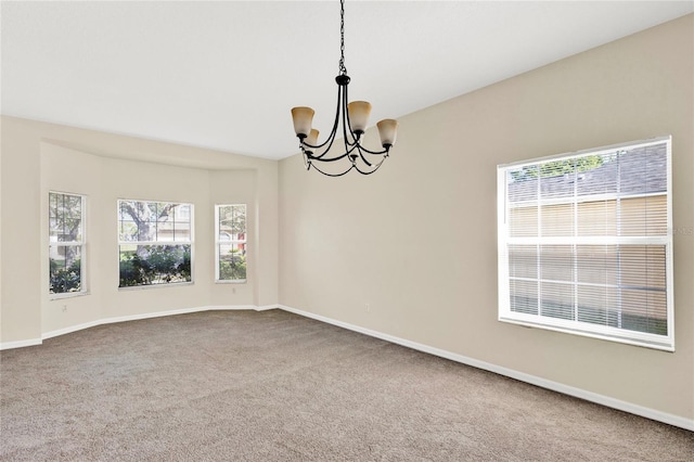 carpeted spare room featuring baseboards and an inviting chandelier