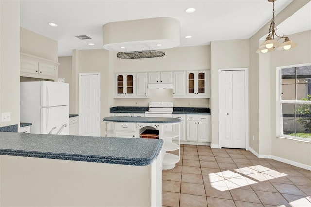 kitchen featuring under cabinet range hood, range with electric stovetop, dark countertops, freestanding refrigerator, and a peninsula