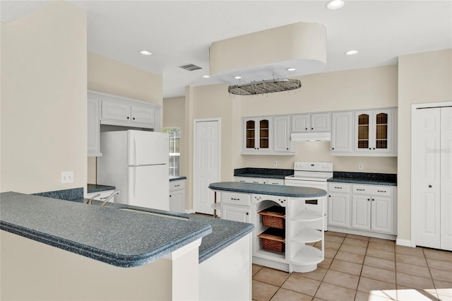 kitchen featuring dark countertops, glass insert cabinets, under cabinet range hood, white appliances, and open shelves