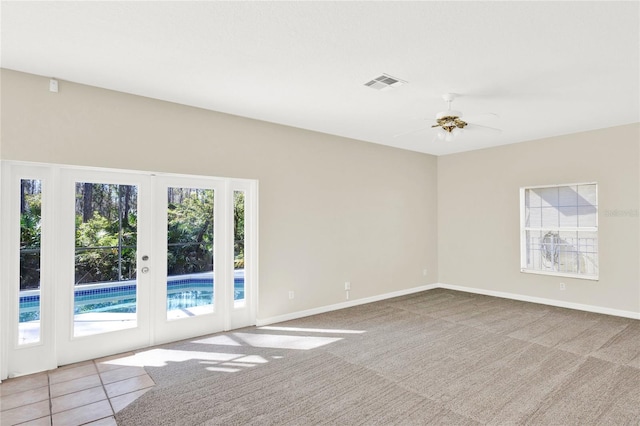 carpeted empty room featuring visible vents, baseboards, ceiling fan, and french doors