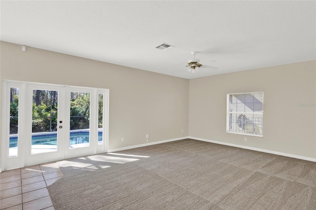 tiled spare room featuring visible vents, french doors, carpet floors, baseboards, and ceiling fan