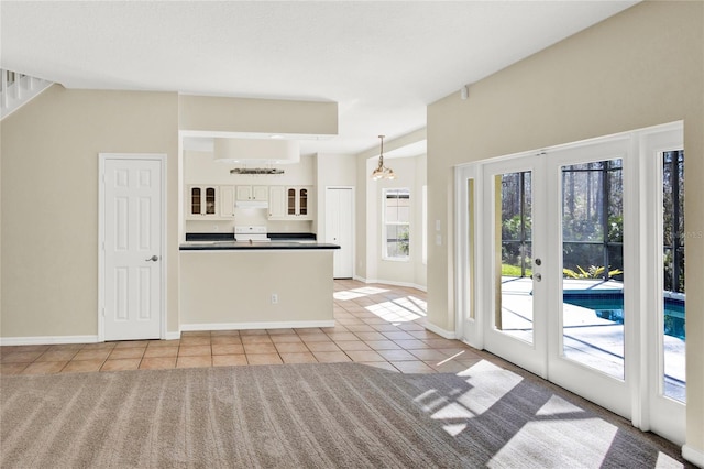 kitchen featuring dark countertops, glass insert cabinets, light tile patterned floors, french doors, and a peninsula