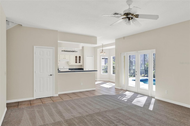 unfurnished living room with tile patterned floors, french doors, baseboards, and carpet