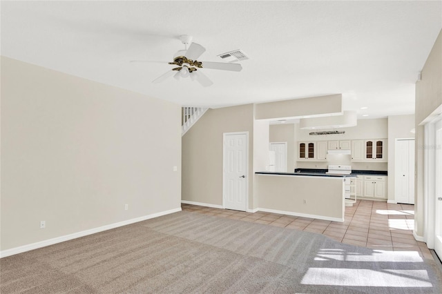 kitchen with ceiling fan, glass insert cabinets, under cabinet range hood, light carpet, and dark countertops