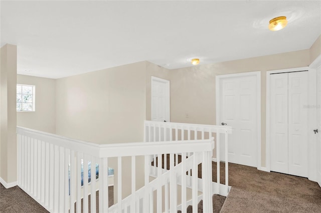 hallway with an upstairs landing, carpet, and baseboards