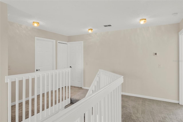 interior space with an upstairs landing, visible vents, baseboards, and light carpet