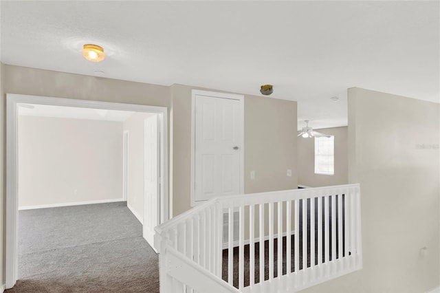 corridor with an upstairs landing, baseboards, and carpet floors