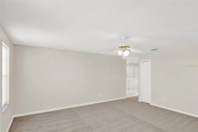 spare room with visible vents, light carpet, a textured ceiling, baseboards, and ceiling fan