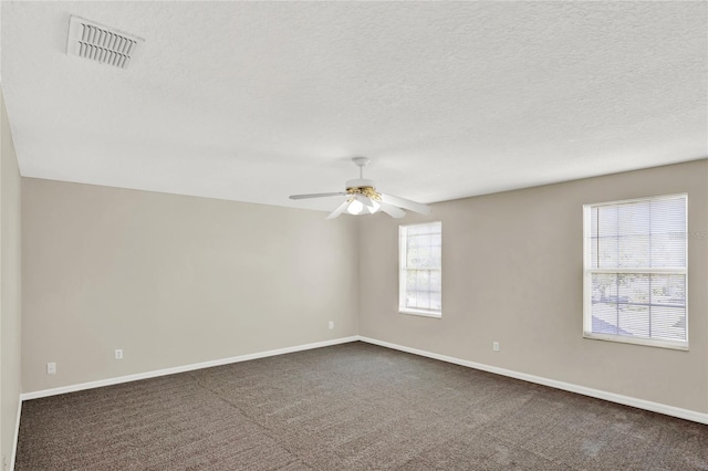 spare room with visible vents, a textured ceiling, ceiling fan, and dark colored carpet