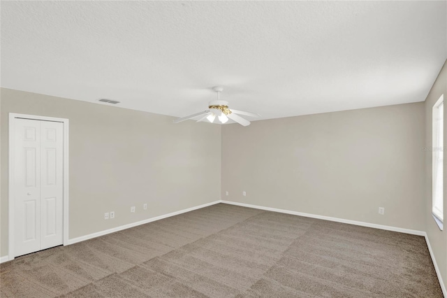 empty room with visible vents, baseboards, carpet floors, a textured ceiling, and a ceiling fan