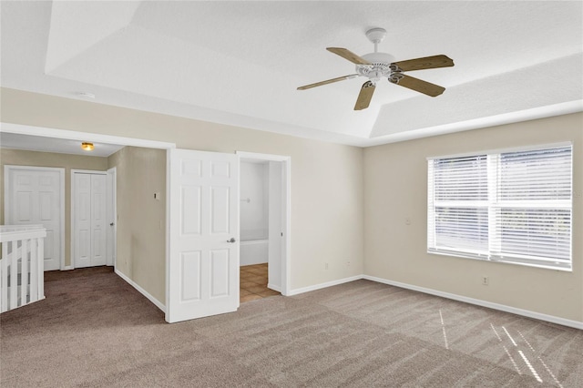 unfurnished room featuring baseboards, carpet flooring, a ceiling fan, and a tray ceiling