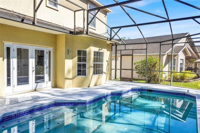 outdoor pool with a lanai, a patio area, and french doors