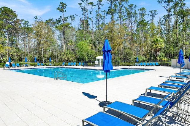 community pool with a patio area and fence