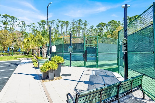 exterior space with a tennis court and fence