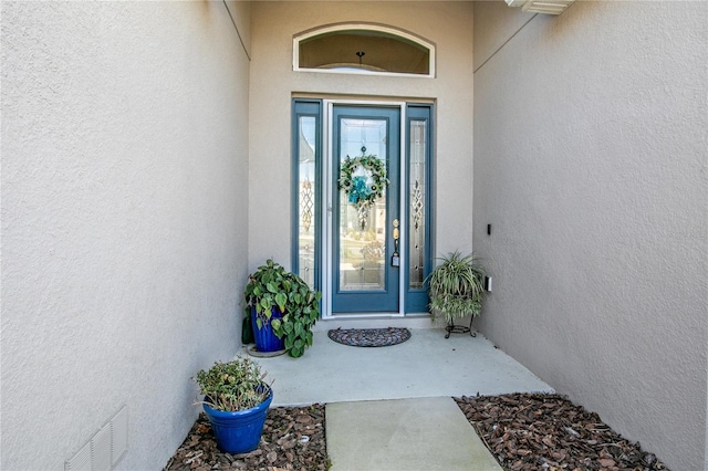 doorway to property with visible vents and stucco siding